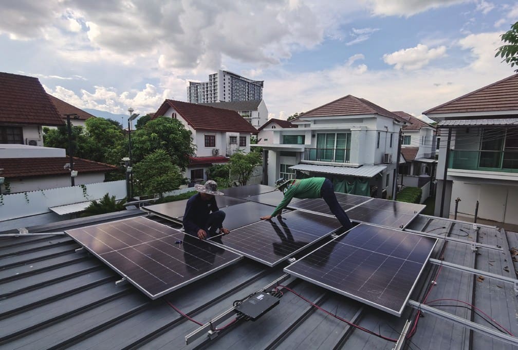 Installers fitting modules on a tiled roof